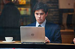 Student sitting in a cafe in a suit using a laptop